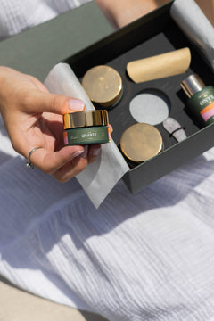 Bálsamo limpiador Quartz GUUDS de 15 ml en la mano, junto a su caja de presentación